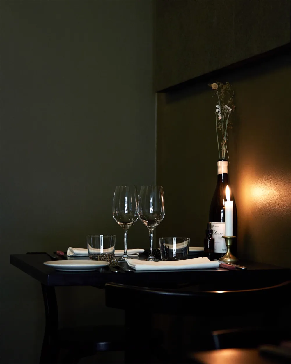 Mesa de restaurante en penumbra con copas y vino